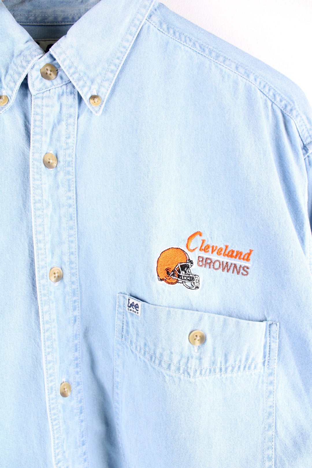 Lee Sport denim shirt in a light blue wash, with the Cleveland Browns team logo embroidered on the chest in orange and brown and a small Lee Sport logo tag.