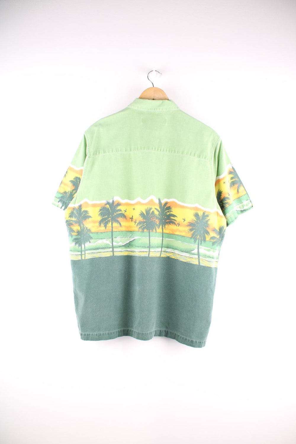 Vintage short-sleeved Hawaiian shirt in green with a front and back design of a beach at sunset, wood-effect buttons, one breast pocket, and a small tab of manufacturer Katin.