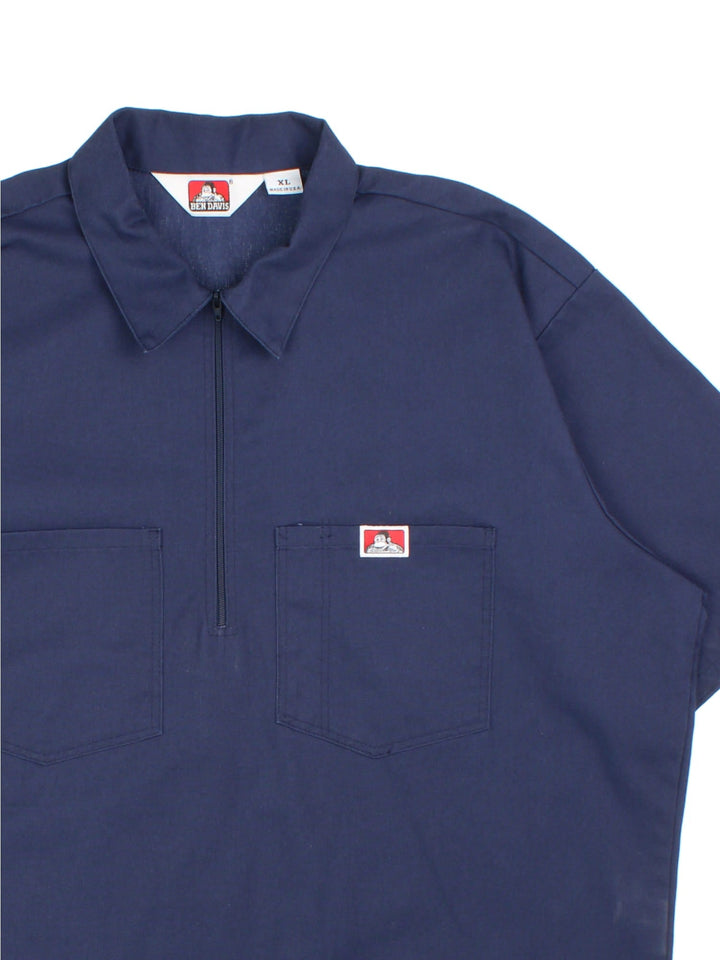 Ben Davis work shirt in a navy blue colourway. The shirt has the classic Ben Davis zip, and double breast pockets, with a pen pocket. Logo is stitched on the front. Made in the USA. 