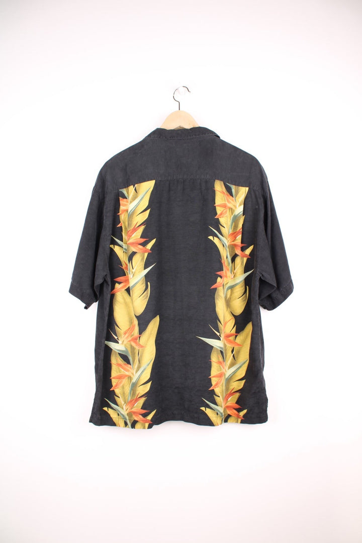 Vintage Tommy Bahama Hawaiian Shirt in a black colourway with floral pattern printed on the front and back, button up with a camp collar and has a chest pocket.