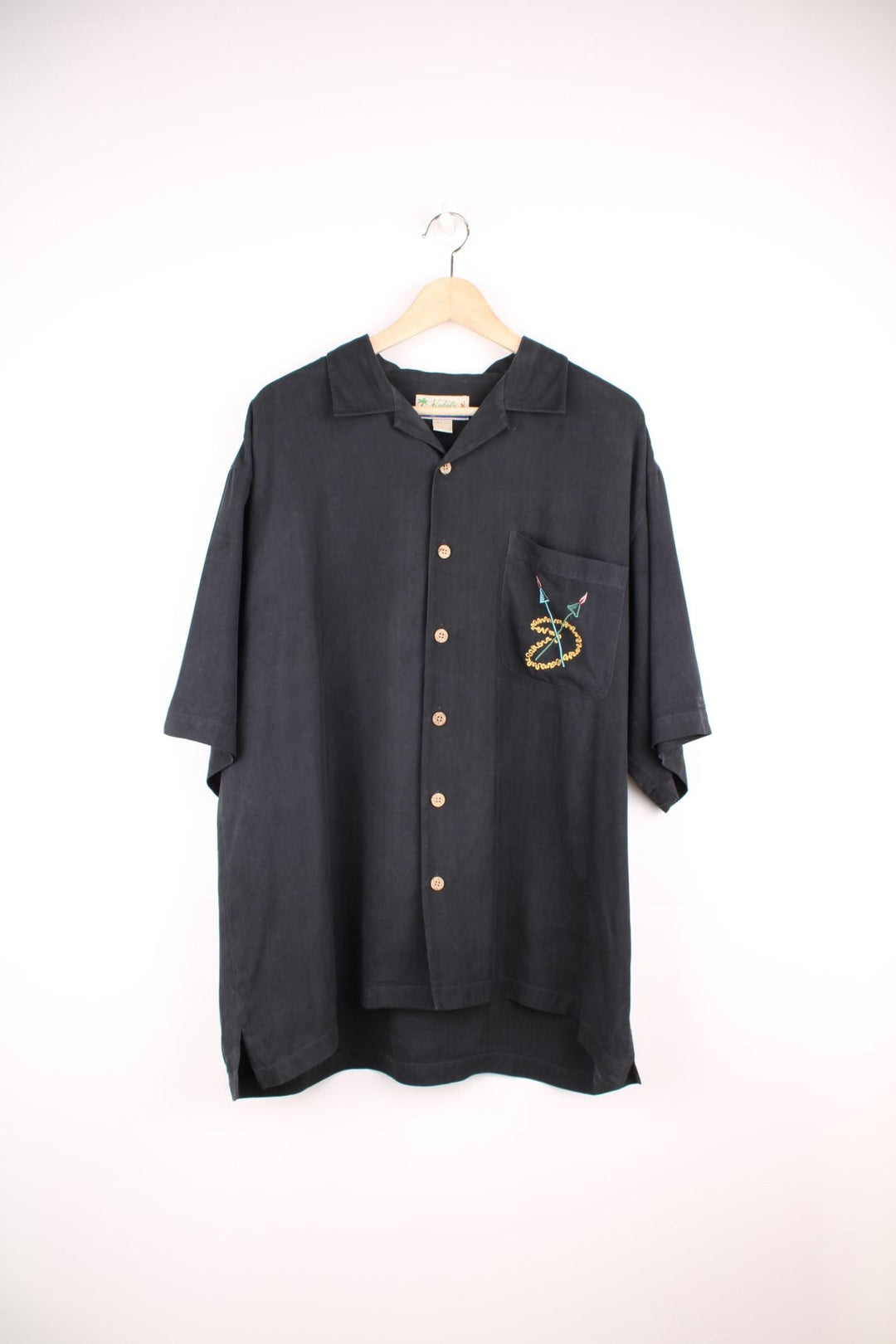 Vintage Kahala Tiki Lounge Hawaiian Shirt in a black colourway with with embroidered tiki lounge design on the front and back, button up with a camp collar, and has a chest pocket.