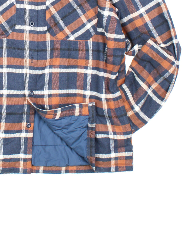 Patagonia Flannel Jacket in a blue, brown and white colourway, button up with double chest pockets, insulated with a quilted lining, and has the logo embroidered on the front.