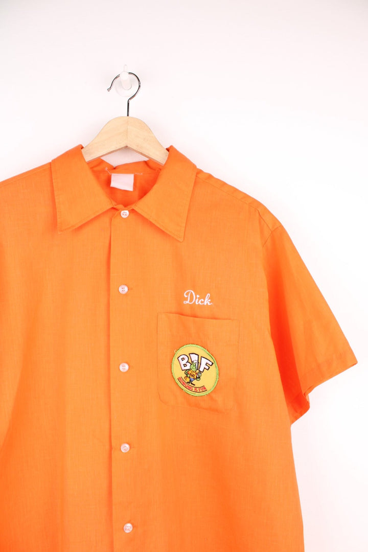 Vintage personalised bright orange short-sleeved bowling shirt with white buttons, a breast pocket, an added patch reading 'BIF Bowling Is Fun'. 