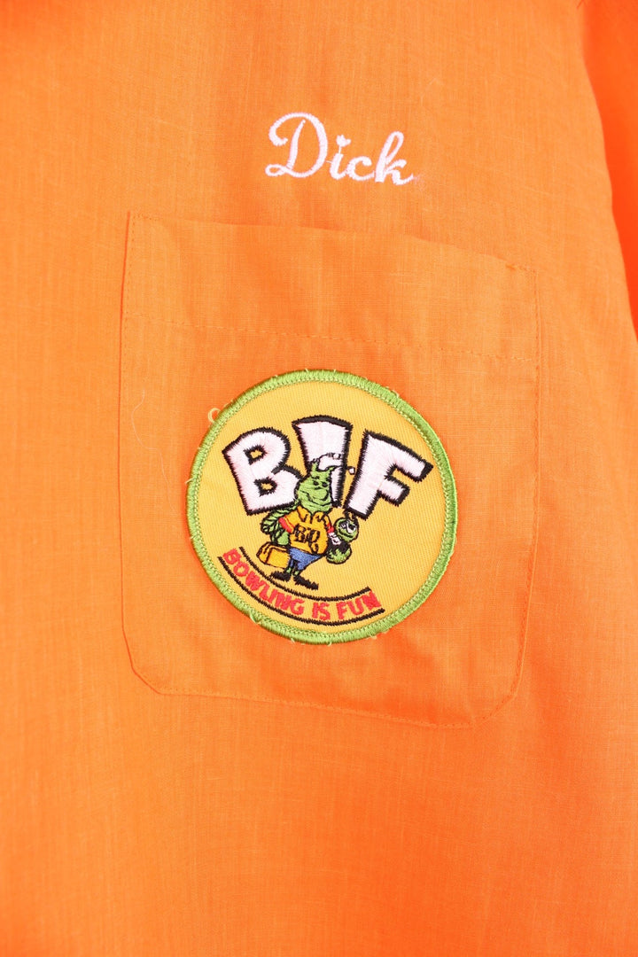 Vintage personalised bright orange short-sleeved bowling shirt with white buttons, a breast pocket, an added patch reading 'BIF Bowling Is Fun'. 