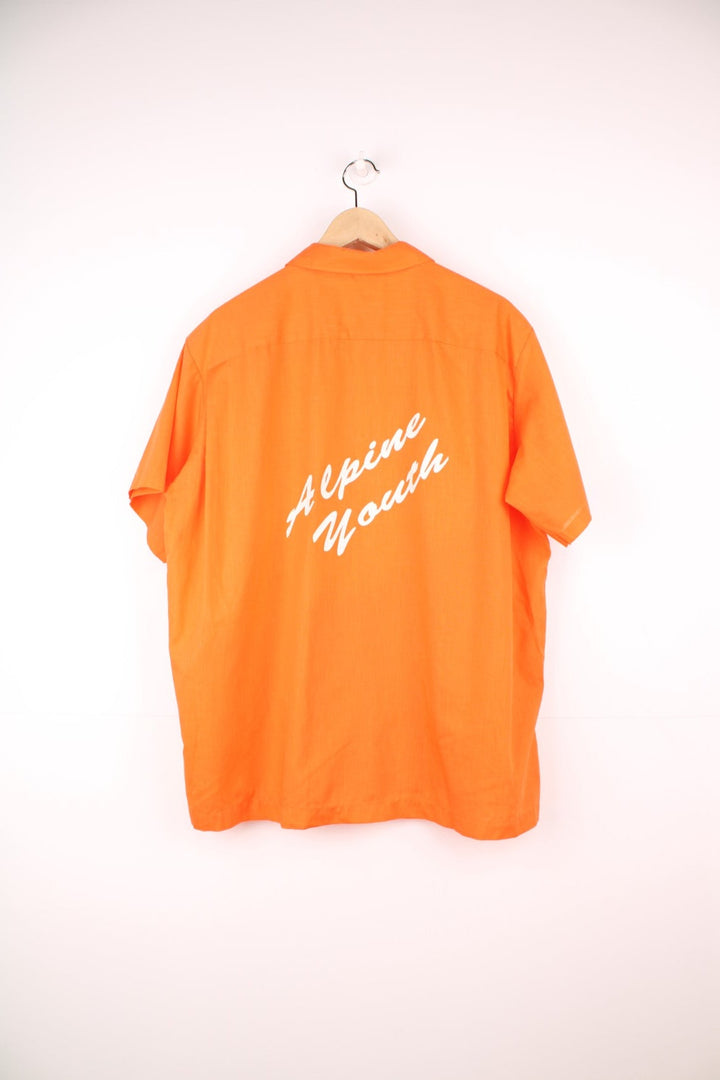 Vintage personalised bright orange short-sleeved bowling shirt with white buttons, a breast pocket, an added patch reading 'BIF Bowling Is Fun'. 