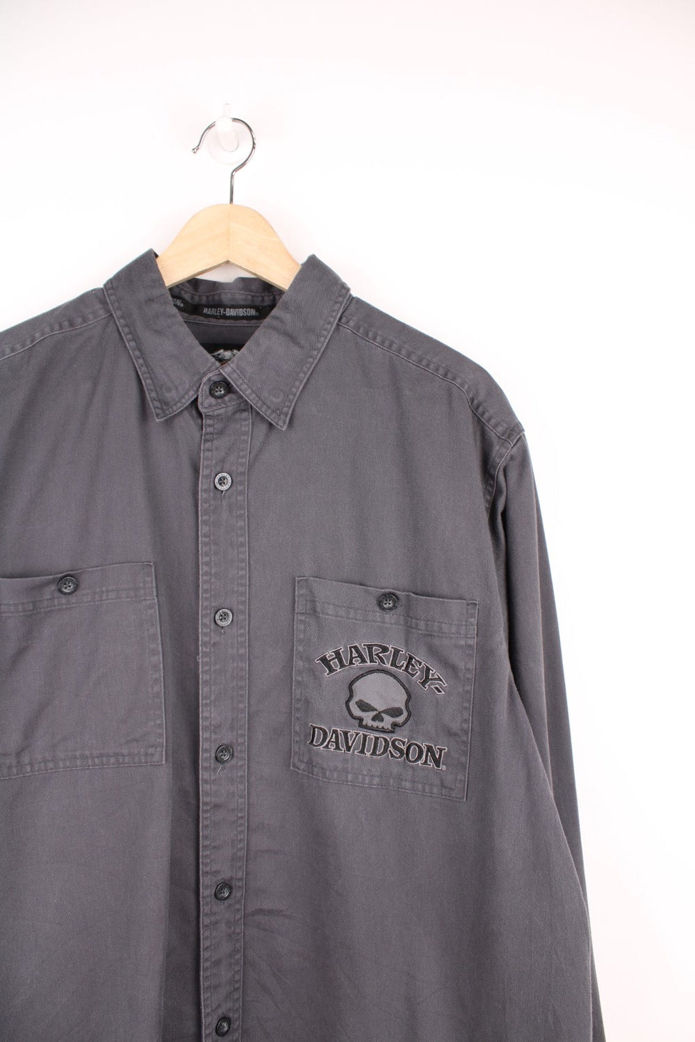 Dark grey Harley Davidson denim shirt with double patch pockets, buttons, and a skull motif and 'Harley Davidson' spellout embroidered on the front left pocket and on the back.  