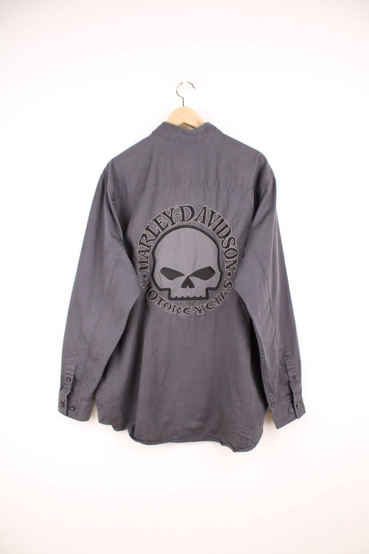 Dark grey Harley Davidson denim shirt with double patch pockets, buttons, and a skull motif and 'Harley Davidson' spellout embroidered on the front left pocket and on the back.  