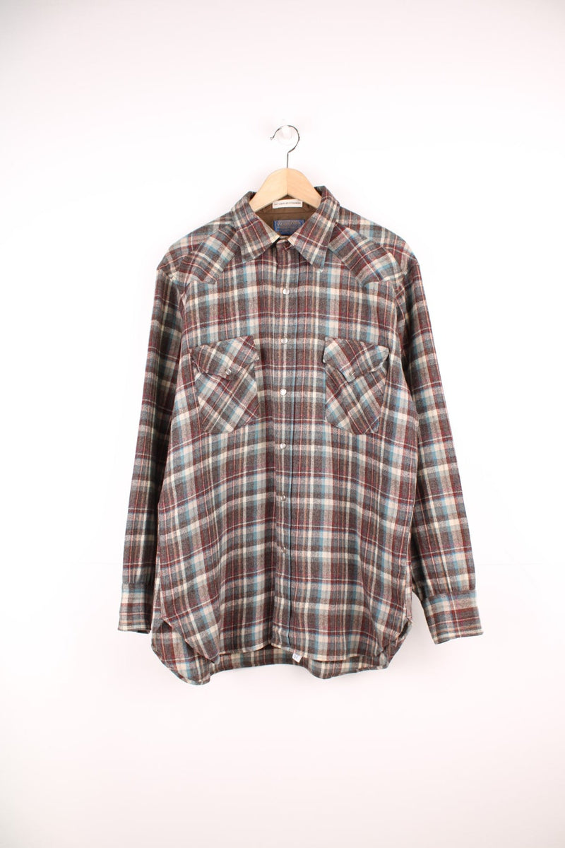 Vintage Pendleton wool plaid Pearl Snap shirt in grey, blue and red. Features chest pockets and Western style yolk. 