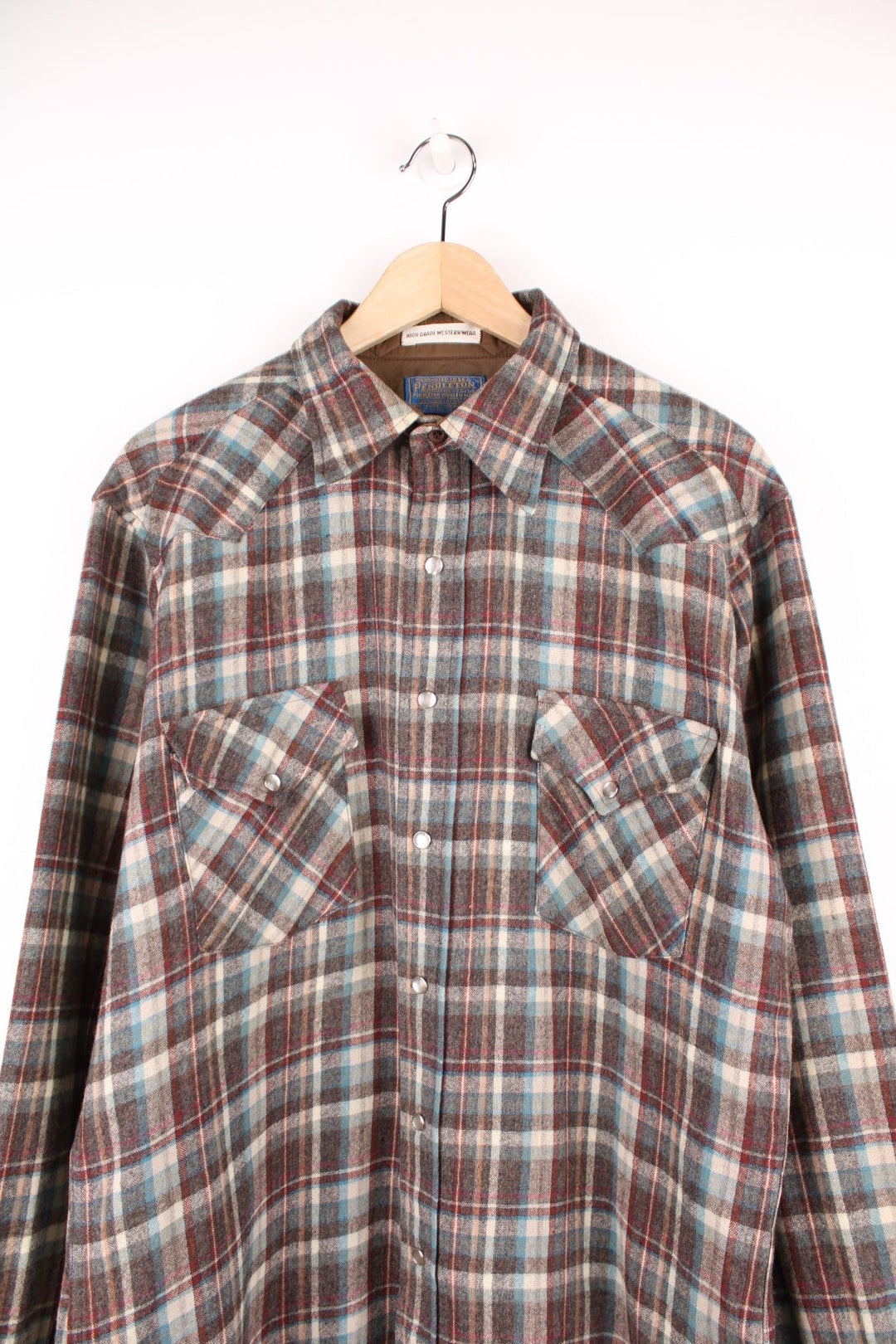 Vintage Pendleton wool plaid Pearl Snap shirt in grey, blue and red. Features chest pockets and Western style yolk. 