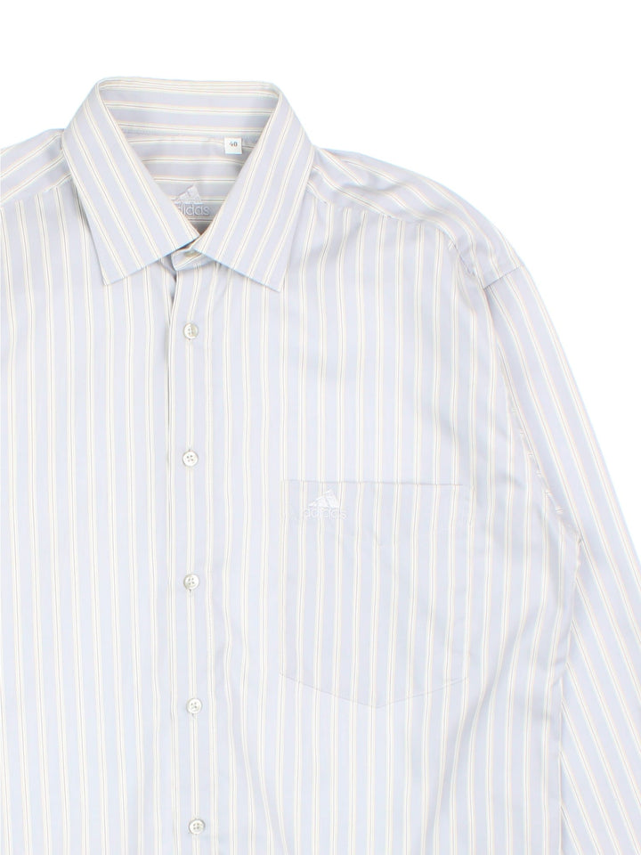 Adidas striped shirt in pale blue, grey and white, with one pocket and a small logo embroidered on.