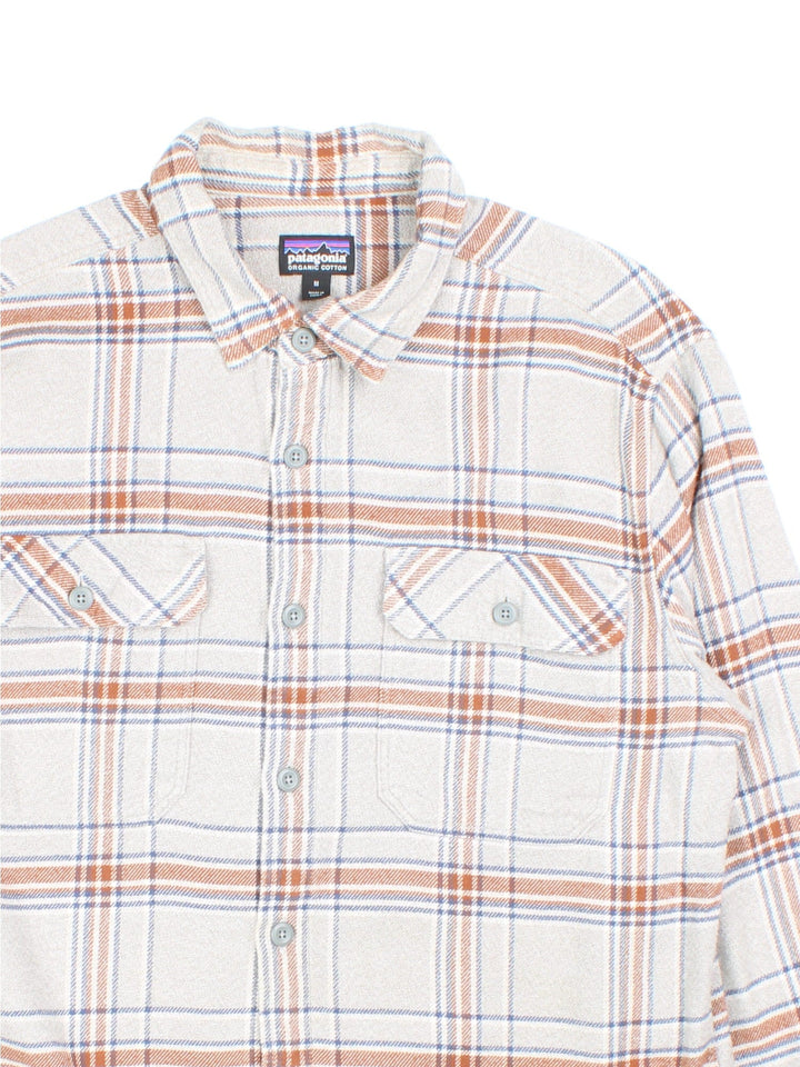 Patagonia flannel shirt in a grey and brown checkered colourway, has two pockets and a small logo tab on the lower left side.