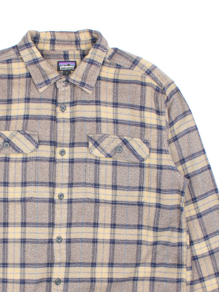 Patagonia check shirt in brown, blue and yellow, with two pockets and a small logo tab on the lower left seam.