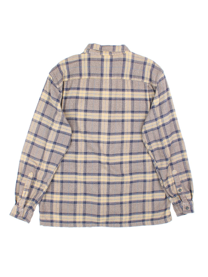 Patagonia check shirt in brown, blue and yellow, with two pockets and a small logo tab on the lower left seam.