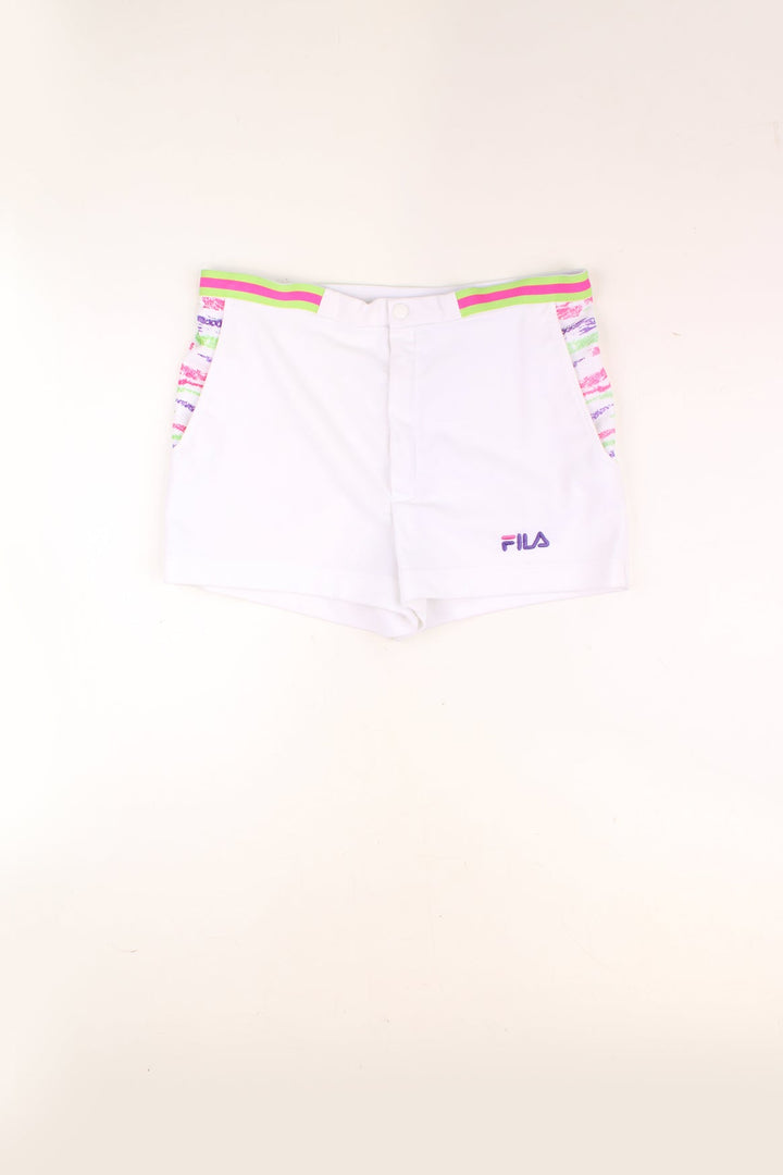 Vintage Fila Tennis Shorts in a white colourway with a multicoloured pattern print by the side pockets, and has the logo embroidered on the front. 