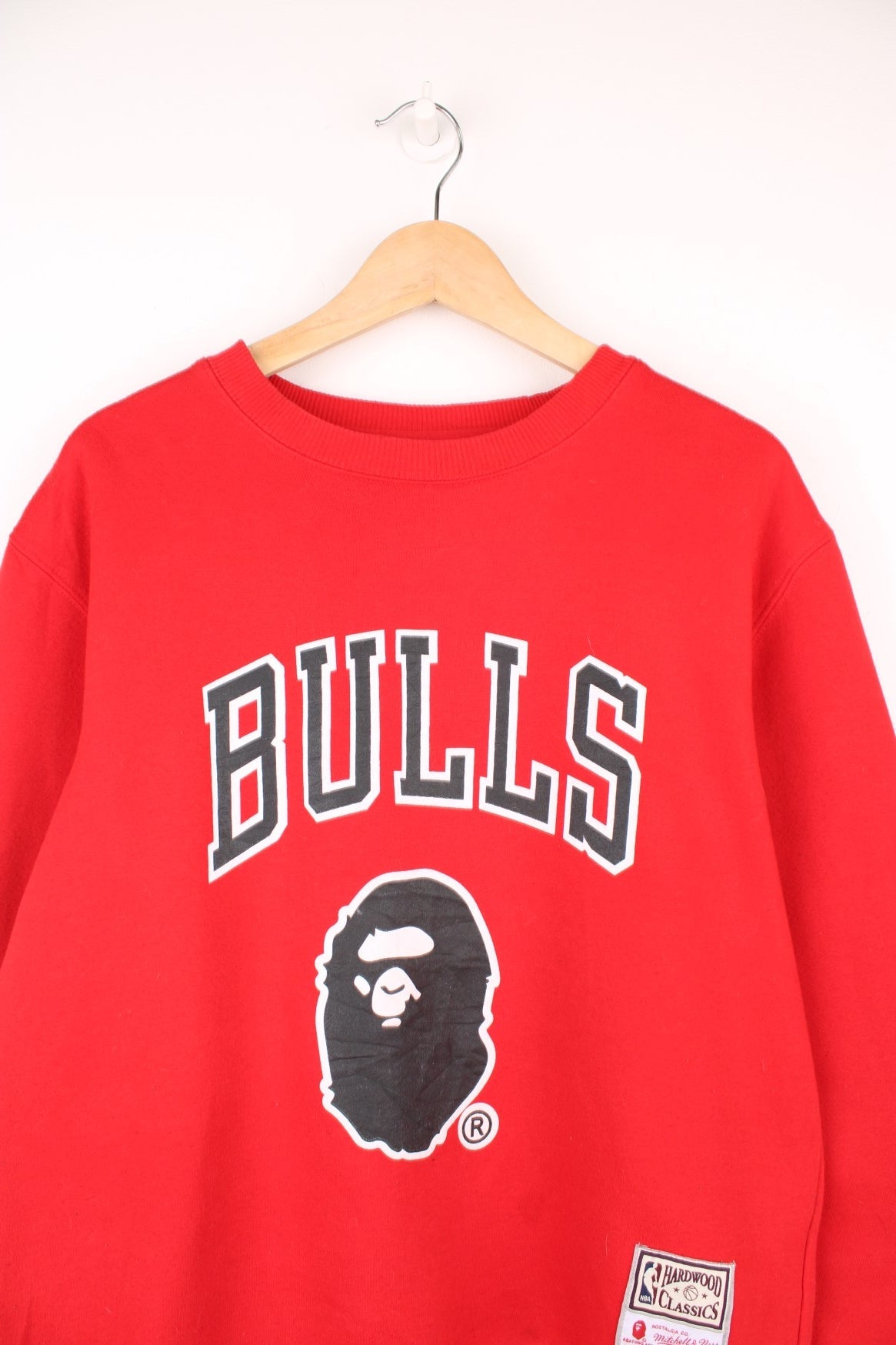 Bape X Mitchell & Ness X NBA Chicago Bulls sweatshirt in red. Features printed spell out Chicago Bulls logo across the chest, signature Bape logo and embroidered Hardwood Classics, Mitchell & Ness badge. 