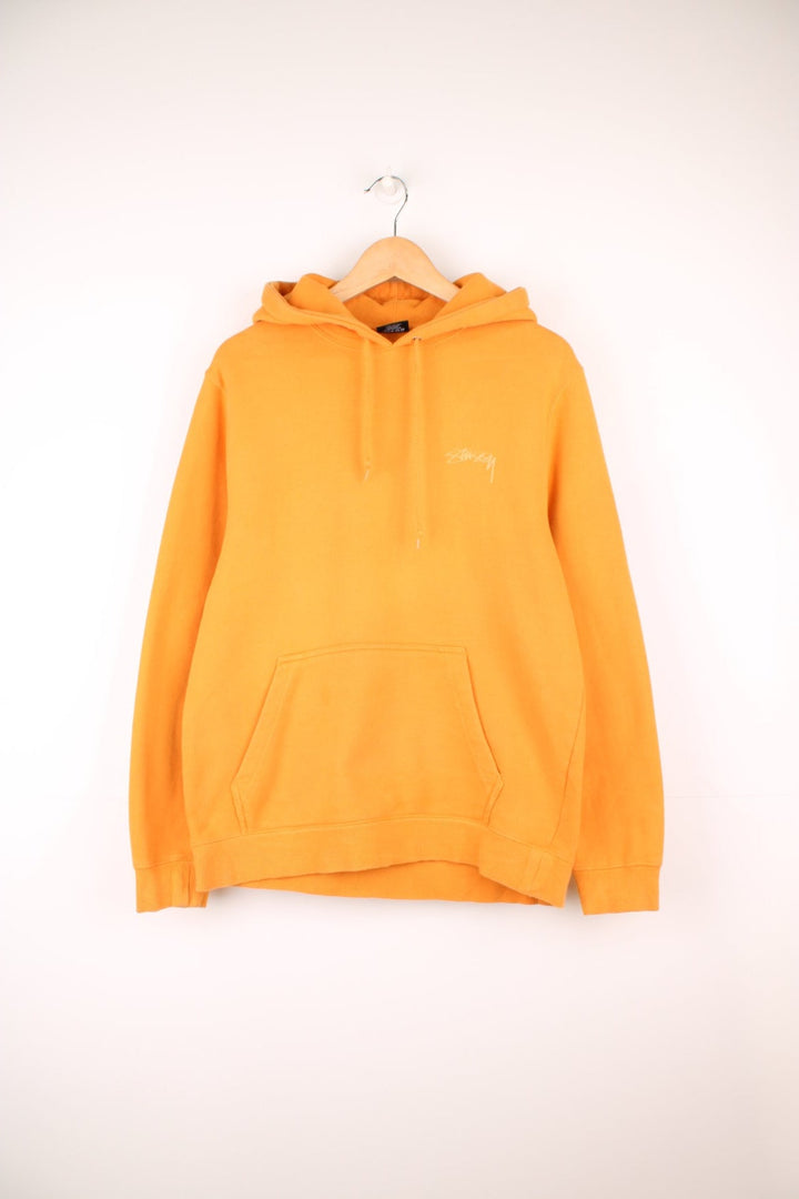 Stussy hoodie in orange with printed logo on the chest and across the back.