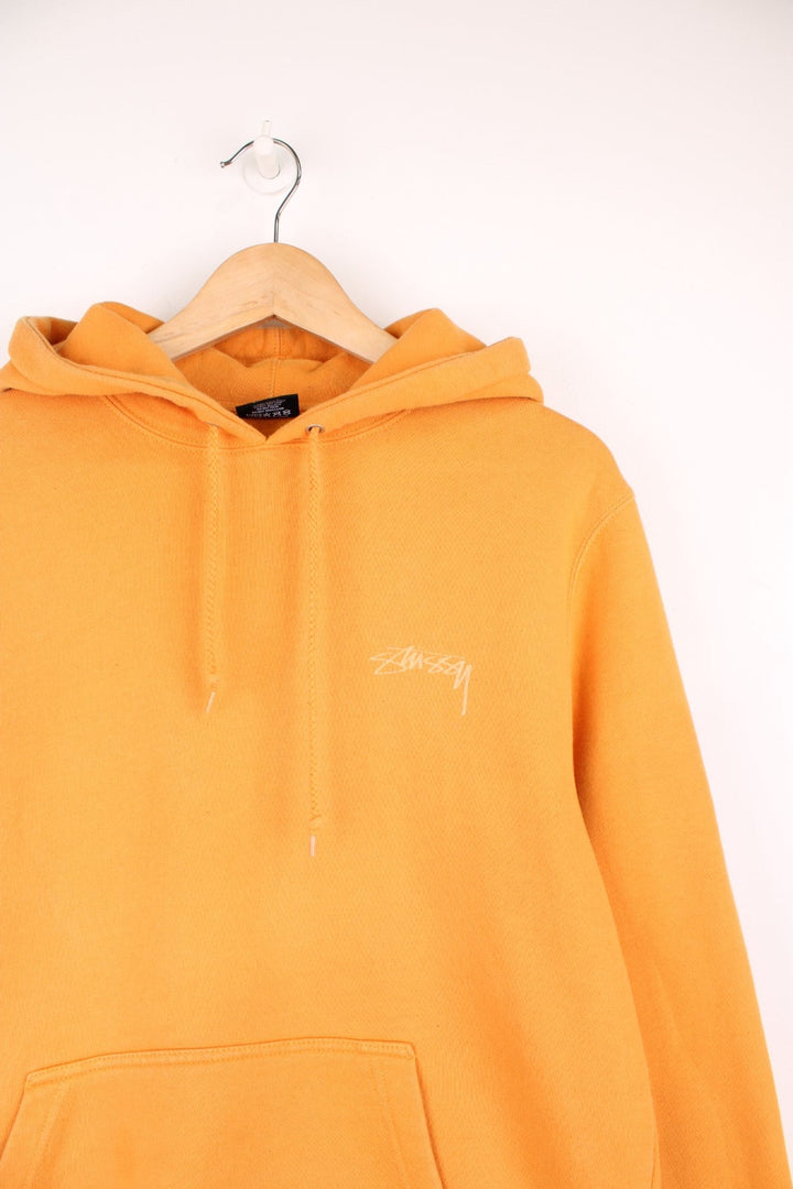 Stussy hoodie in orange with printed logo on the chest and across the back.