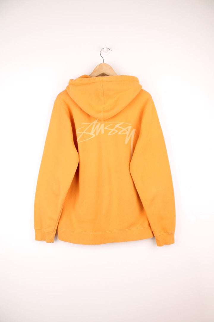 Stussy hoodie in orange with printed logo on the chest and across the back.