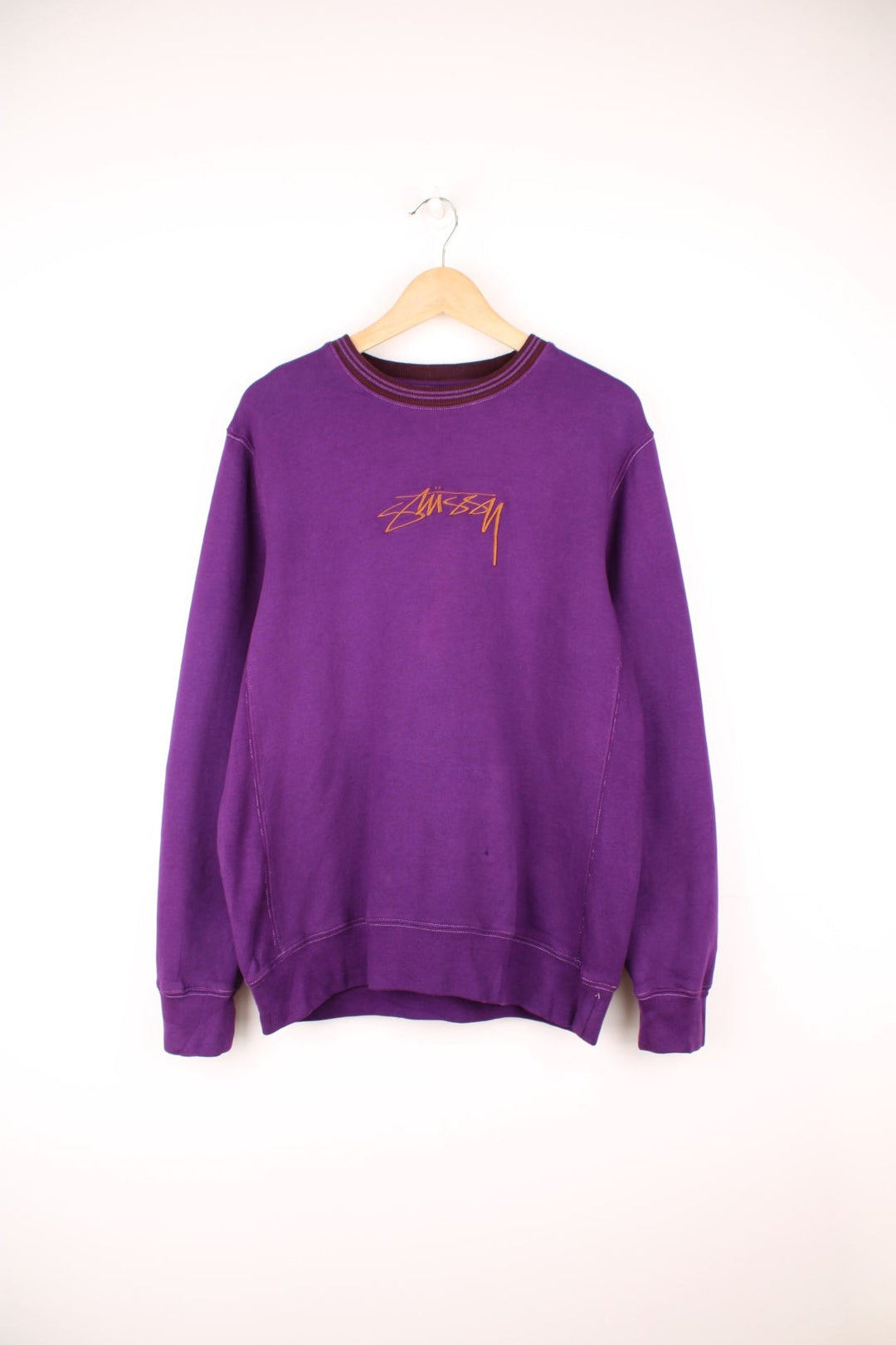 Stussy crew neck sweatshirt in purple with a contrast collar and embroidered logo across the chest in brown.