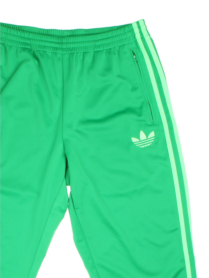 Adidas trefoil tracksuit bottoms in green with the three-stripe detail going down the sides, an elasticated waist, and two zipped pockets.