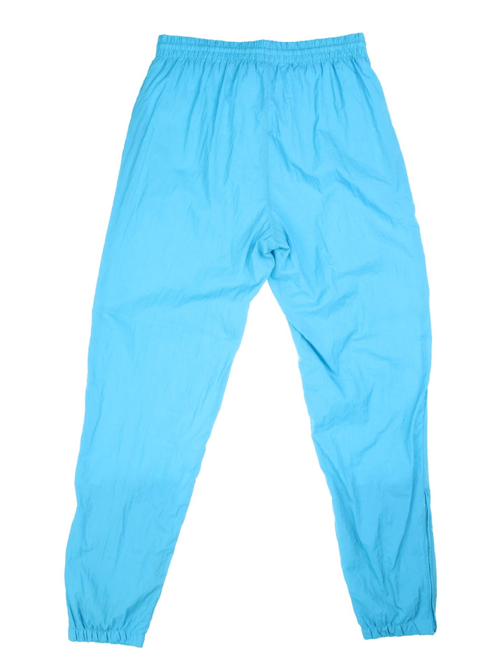 90s Lotto tracksuit bottoms in blue with two zipped pockets, an elasticated waist, and an embroidered logo in purple.