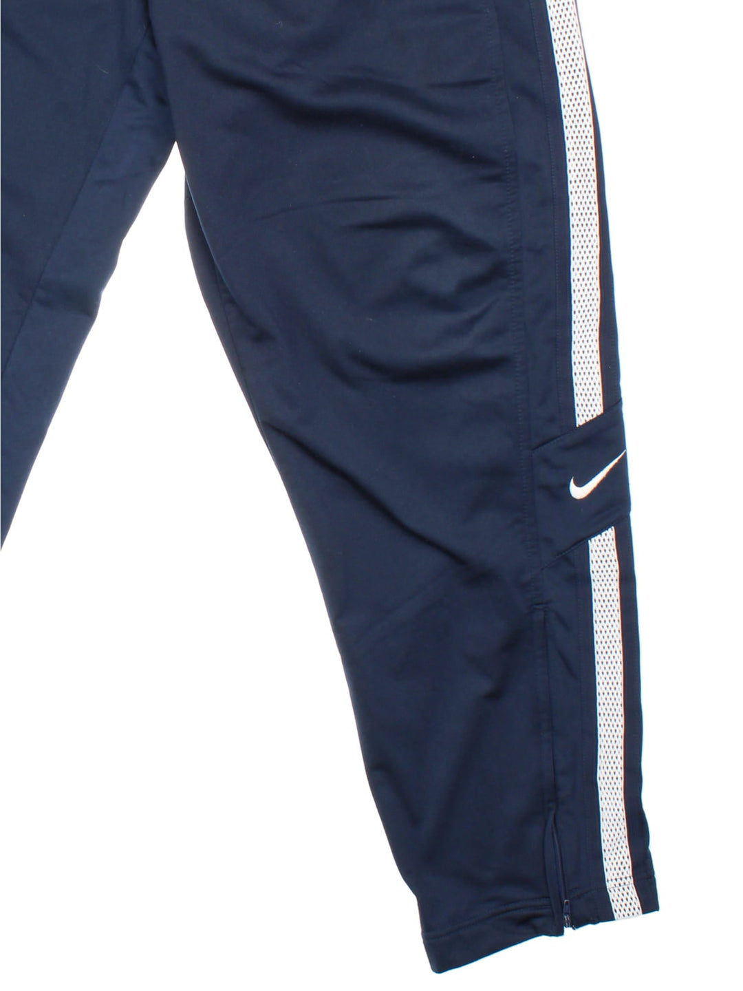 Nike tracksuit bottoms in navy blue with white tape detailing, an elasticated waist, two zipped pockets, and embroidered swoosh logos in white.