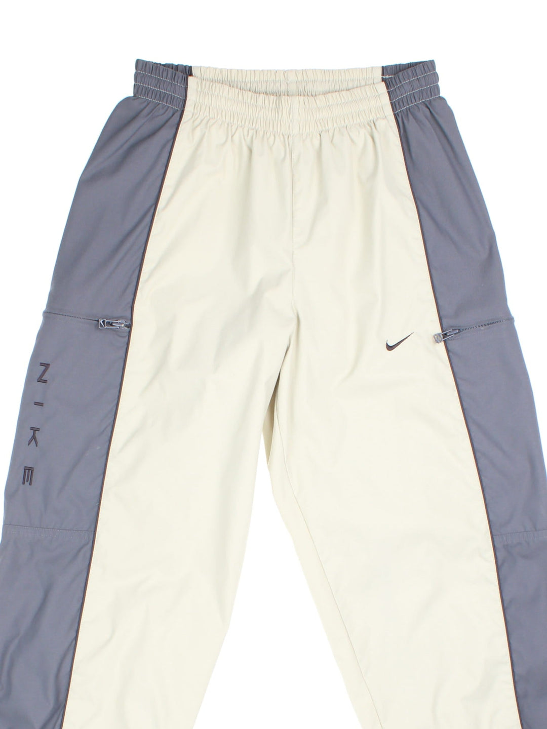 Nike 90s tracksuit bottoms in tan and grey with two zipped pockets, an elasticated waist, and an embroidered swoosh logo.