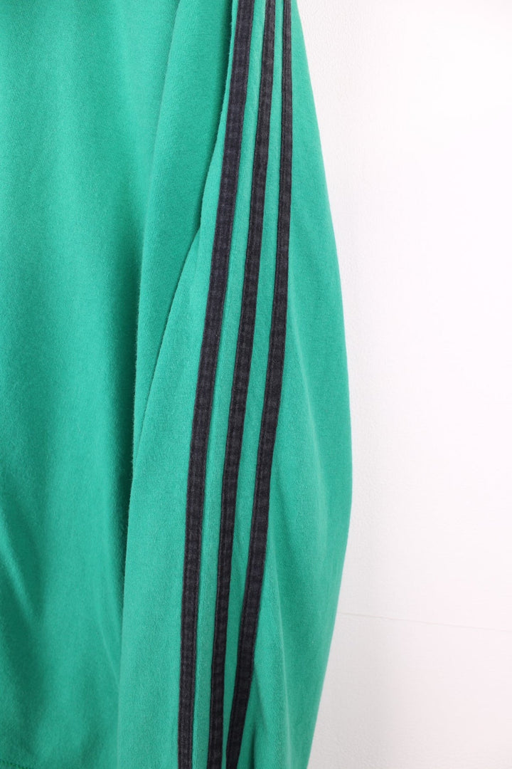 Vintage 1990s longsleeved Adidas T-Shirt in a green colourway with the Adidas logo embroidered on the front and three stripes stitched down the sleeves.