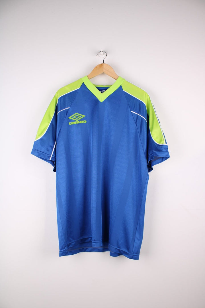 Vintage 1990s Umbro T-Shirt in ablue colourway with lime green accents and white piping on the shoulders and sleeves. The shirt has the Umbro logo embroidered on the front. 