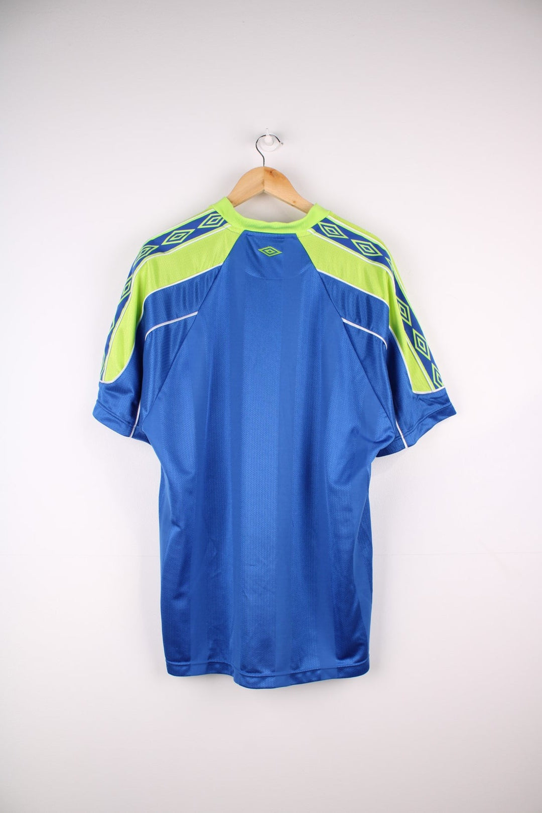 Vintage 1990s Umbro T-Shirt in ablue colourway with lime green accents and white piping on the shoulders and sleeves. The shirt has the Umbro logo embroidered on the front. 