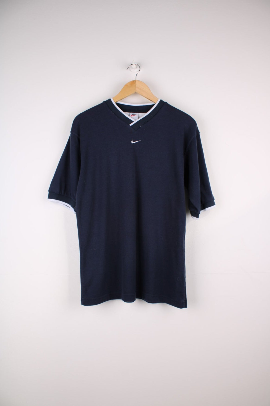 1990s Nike T-Shirt in a navy blue colourway. The T shirt has a V neck, cuffed sleeves and a small embroidered logo on the front.  