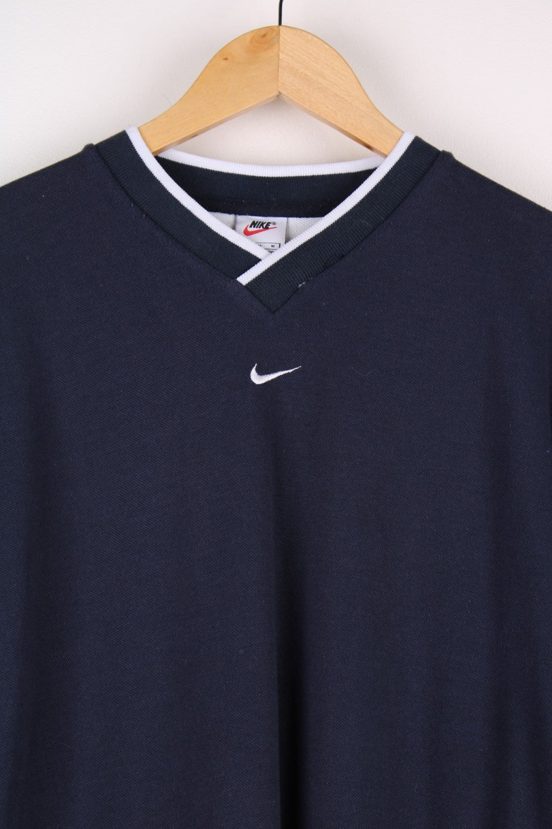 1990s Nike T-Shirt in a navy blue colourway. The T shirt has a V neck, cuffed sleeves and a small embroidered logo on the front.  