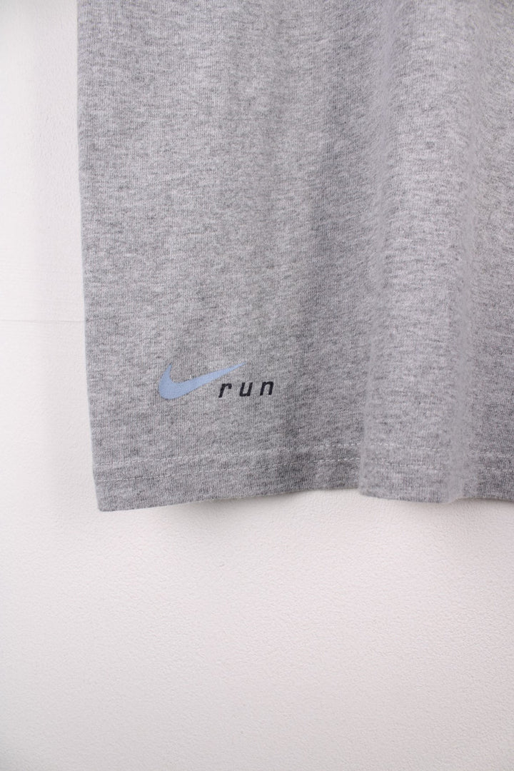 Vintage Nike Run T-Shirt in a grey colourway with a small shoe graphic printed on the front. The shirt has a V neck and capped sleeves. 