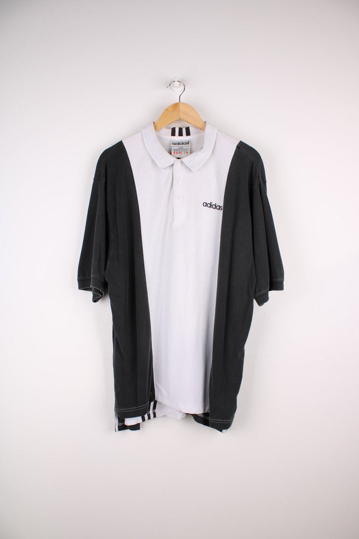 Vintage Adidas polo shirt in a white colourway with black panels on the sides and sleeves. The shirt has three stripes down the back, and the Adidas logo embroidered on the front. .