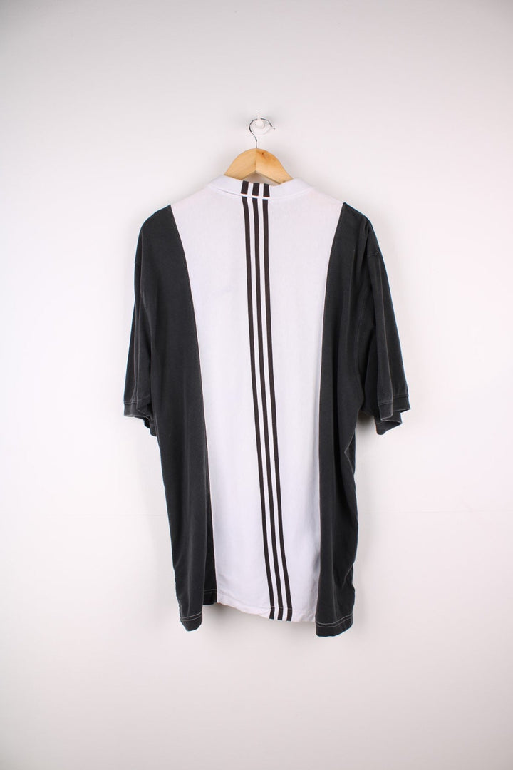 Vintage Adidas polo shirt in a white colourway with black panels on the sides and sleeves. The shirt has three stripes down the back, and the Adidas logo embroidered on the front. .