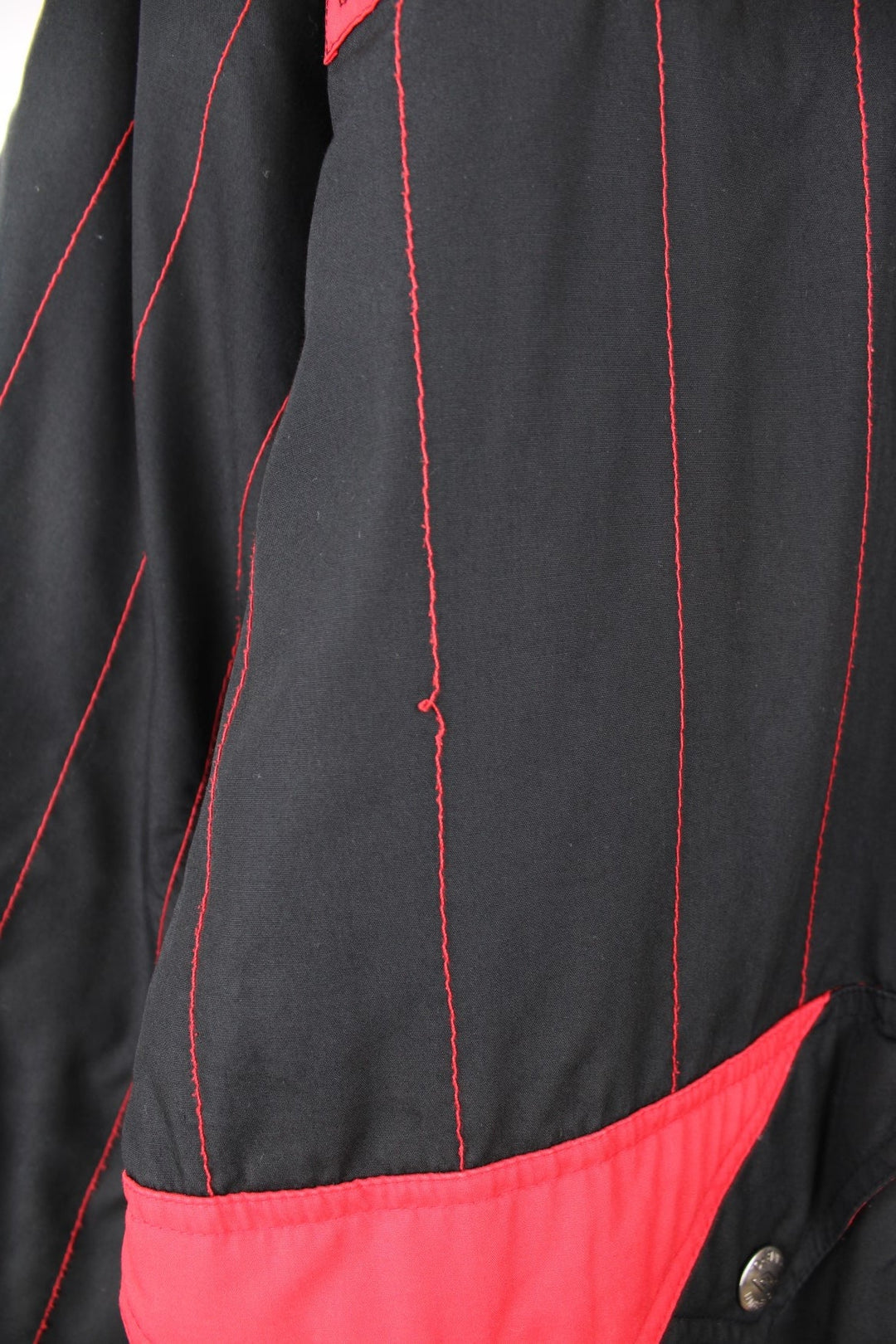 1993/95 Manchester United Umbro Training Coat in a black and red colourway with stripes throughout, zip up with side pockets, insulated with a quilted lining, and has the logos embroidered on the front and back.