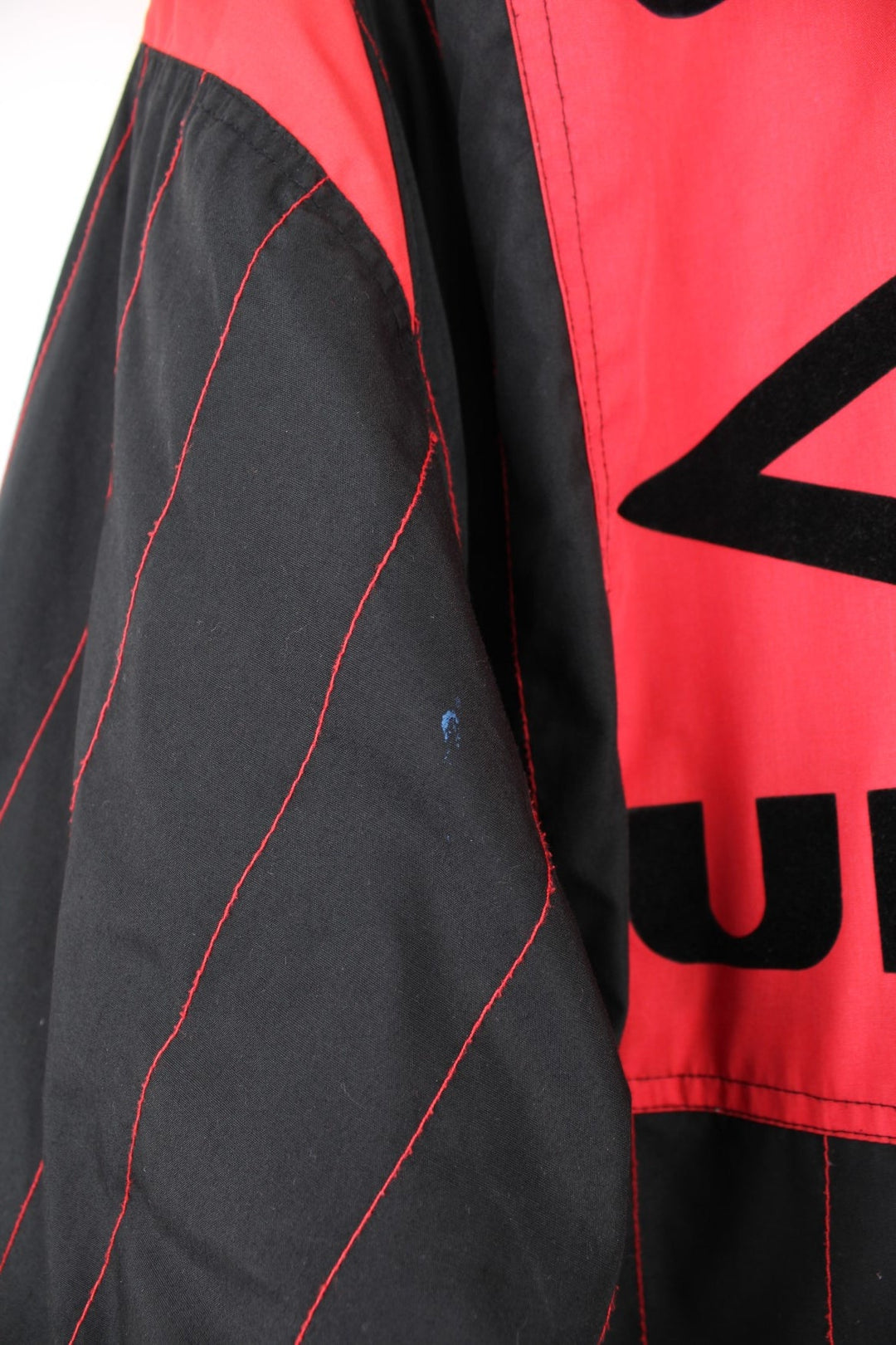 1993/95 Manchester United Umbro Training Coat in a black and red colourway with stripes throughout, zip up with side pockets, insulated with a quilted lining, and has the logos embroidered on the front and back.