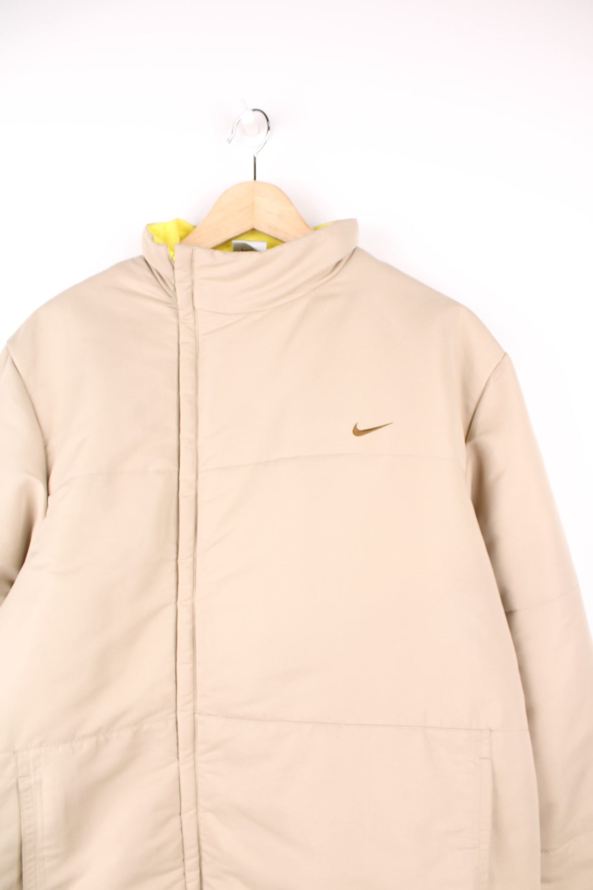 Nike Puffer Coat in a tanned colourway, zip up with side pockets, and has the swoosh logo embroidered on the front. 