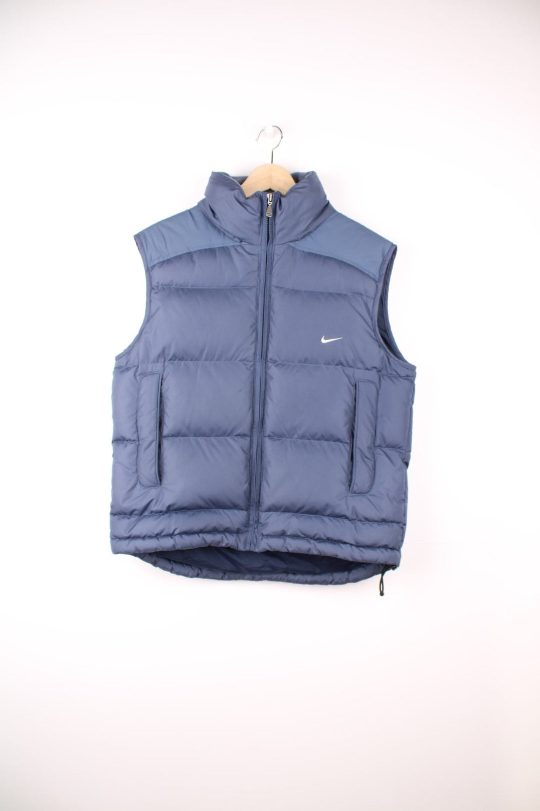 Nike Puffer Gilet in a blue colourway, zip up with side pockets, insulated lining, hidden hood, and has the swoosh logo embroidered on the front. 