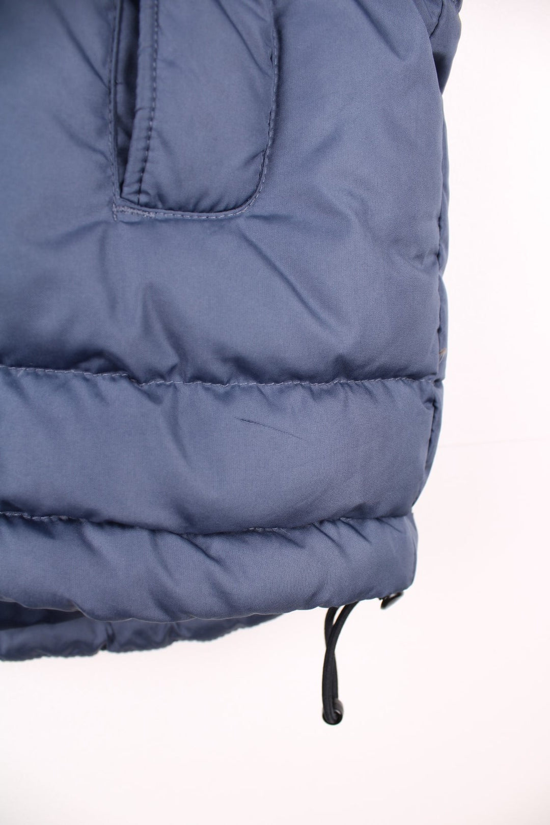 Nike Puffer Gilet in a blue colourway, zip up with side pockets, insulated lining, hidden hood, and has the swoosh logo embroidered on the front. 