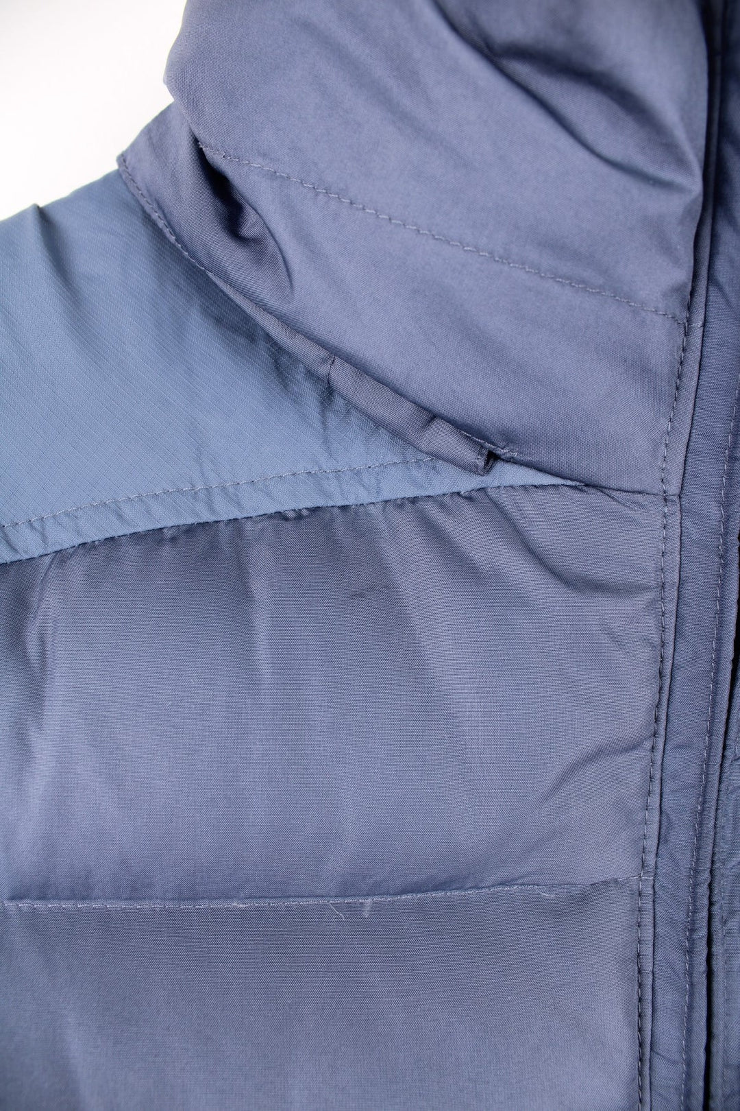 Nike Puffer Gilet in a blue colourway, zip up with side pockets, insulated lining, hidden hood, and has the swoosh logo embroidered on the front. 