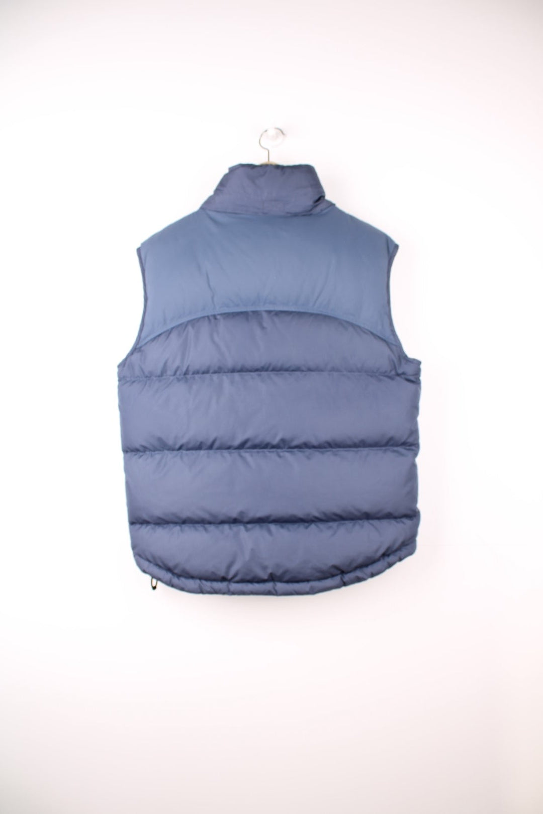 Nike Puffer Gilet in a blue colourway, zip up with side pockets, insulated lining, hidden hood, and has the swoosh logo embroidered on the front. 