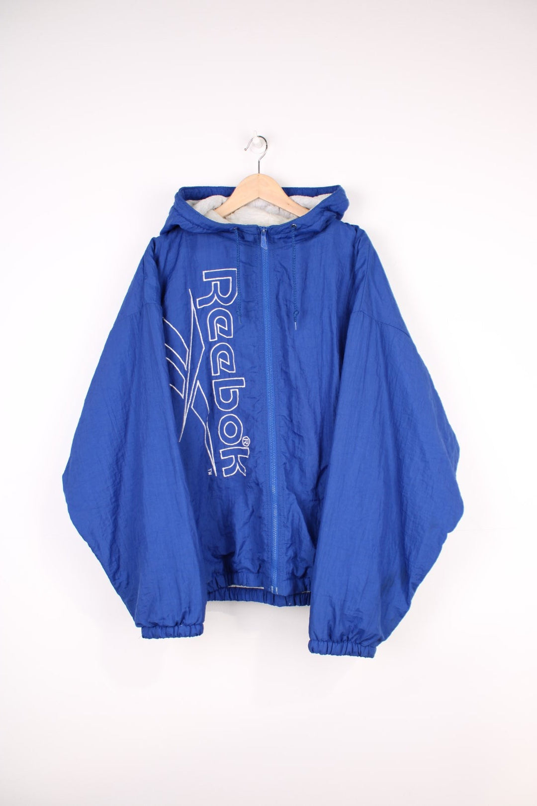 Reebok Jacket in a blue colourway, zip up with side pockets, insulated with a heavy cotton lining, hooded, and has the spell out logo embroidered down the front. 