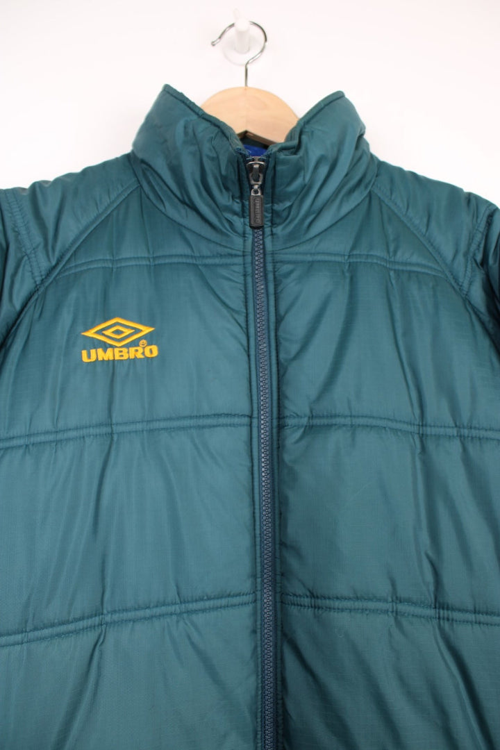 Umbro Puffer Coat in a blue colourway, zip up with side pockets, insulated, and has the logo embroidered on the front. 