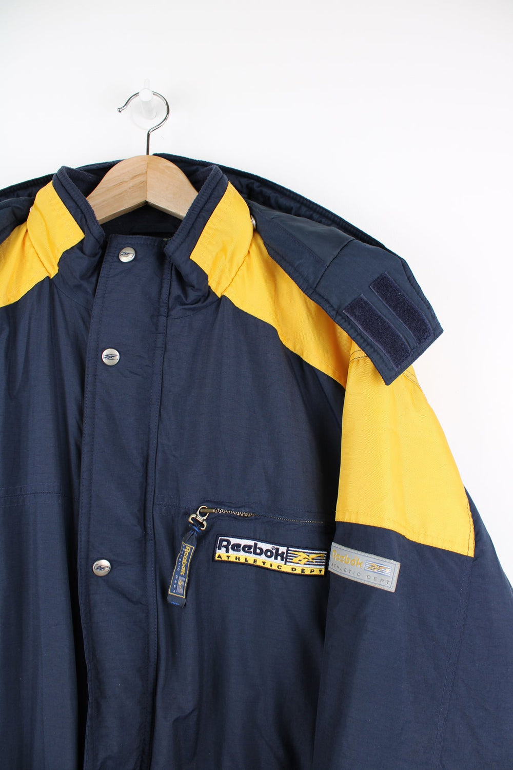 Vintage Reebok Athletic Dept blue and yellow coat. Features removable hood and embroidered logo.