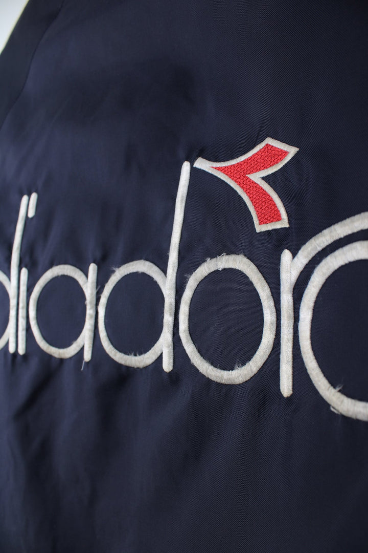 Vintage blue and red Diadora coat featuring embroidered logo on the front and back.