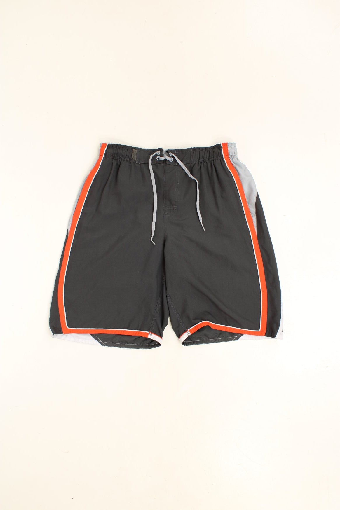 Nike Shorts in a grey, orange and white colourway with stripes going around the back and sides, has an ajdustable waist, side pockets, netted lining, and the logo embroidered on the back. 