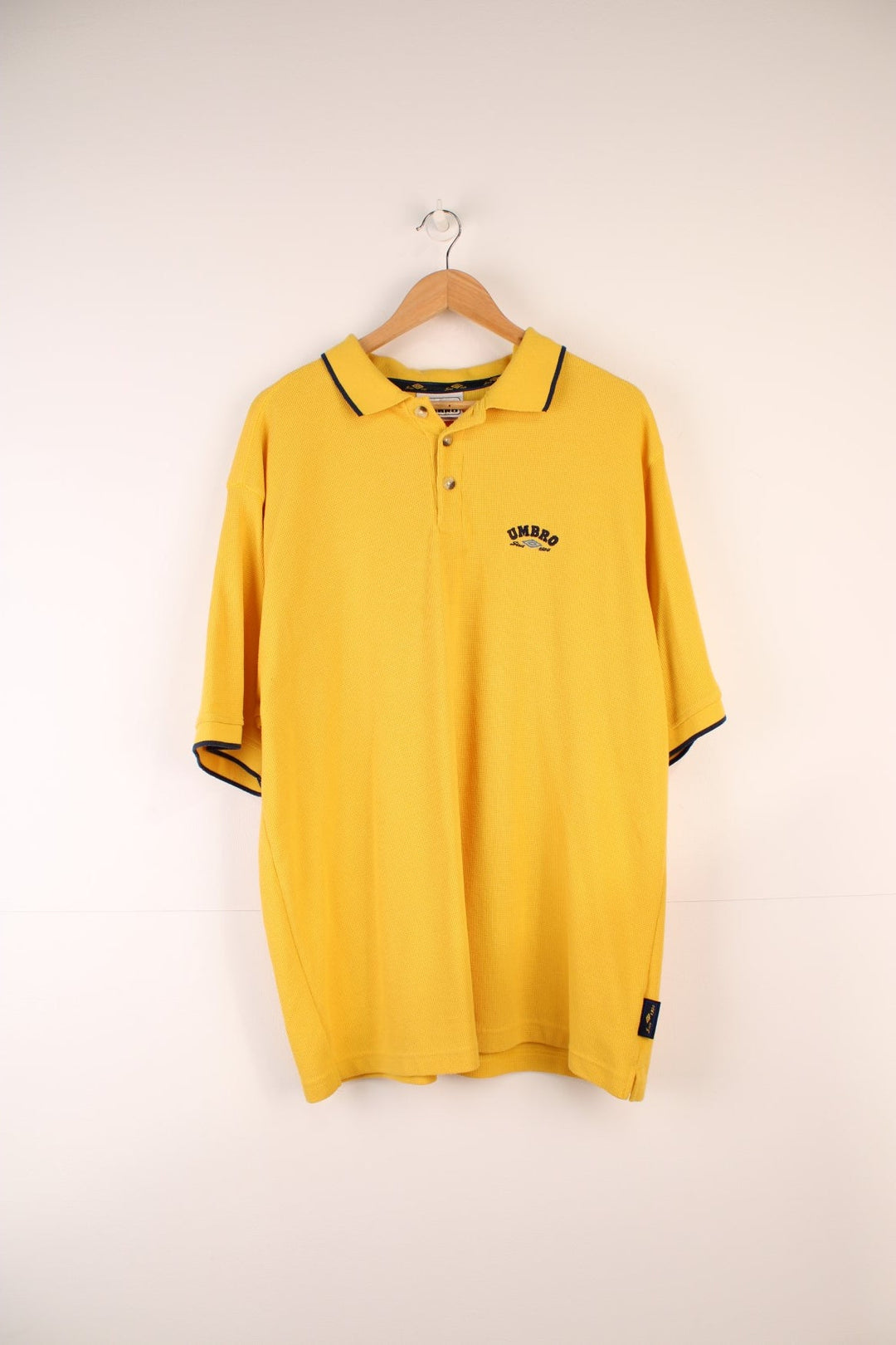 Umbro Polo Shirt in a yellow colourway with navy stripes going round the end of the cuffs and collar, button up, and has the logo embroidered on the front.