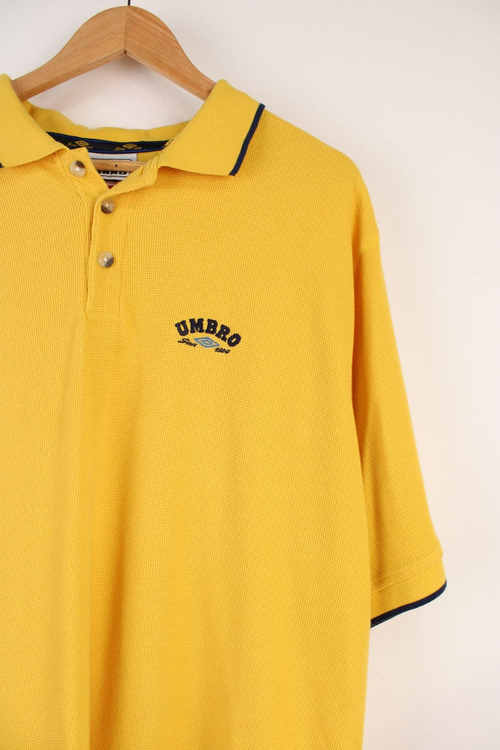 Umbro Polo Shirt in a yellow colourway with navy stripes going round the end of the cuffs and collar, button up, and has the logo embroidered on the front.