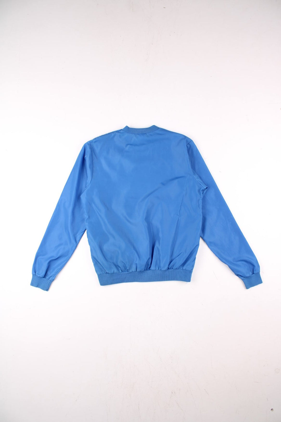 Vintage Nike pullover drill / training top in a blue shower-proof material, with two pockets, an embroidered swoosh logo, and a zipped opening on the left shoulder.